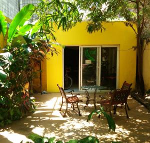 Haikou Banana Hostel في هايكو: فناء فيه كراسي وطاولة امام بيت اصفر