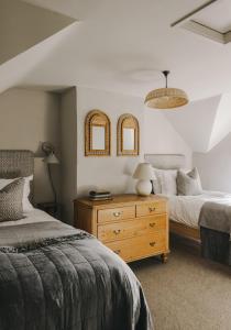 a bedroom with two beds and a dresser with two mirrors at The Workers Cottage in Great Bircham