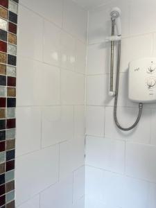 a shower in a bathroom with a white tile wall at Rj s house in Merthyr Tydfil