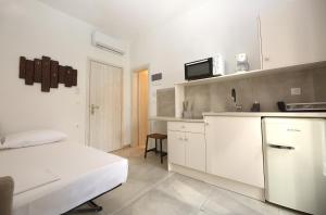 Una habitación blanca con una cama y una cocina. en Marousos Central Guesthouse, en Portaria