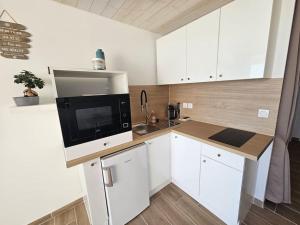 a small kitchen with a microwave and a sink at Appartement 4 pers vue mer le barcares in Dosse Gros +1 photo