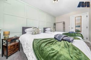 a bedroom with two beds with green sheets and a table at Elegant 2Bed Sleeps 4 With Parking in Paisley