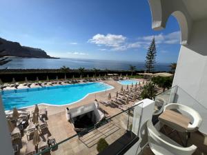 a view of a swimming pool with chairs and the ocean at Cura Sea View Apartment in Playa del Cura