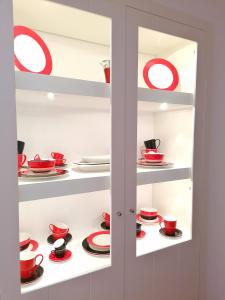 a cupboard filled with red cups and plates at Villa Martin in Óbidos