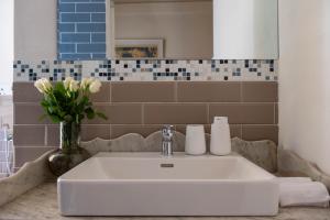 a bathroom sink with a vase of flowers and a mirror at Blue House 9 Rooms & Breakfast in Birgu +81 photos