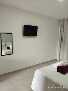 um quarto com uma televisão numa parede branca em Pousada Porto Feliz em Porto Seguro