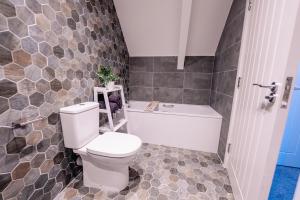 a bathroom with a white toilet and a bath tub at LUXURY SPACIOUS 2-BED & High Ceiling in Cardiff