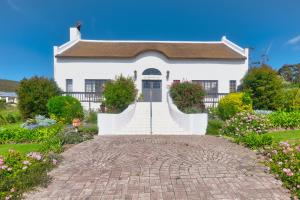 a white house with a brick driveway at Grace Courtyard Cottage in Bredasdorp