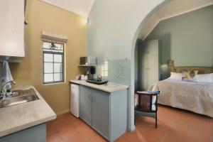 a kitchen with a sink and a bed in a room at Grace Courtyard Cottage in Bredasdorp