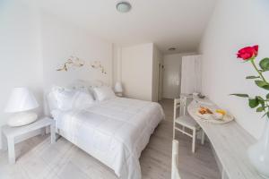 a white bedroom with a white bed and a table at Hotel La Settima Luna in Savudrija