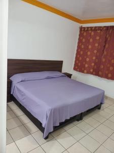 Un dormitorio con una cama con sábanas moradas y una ventana. en Cortes Hermanos, en La Cal