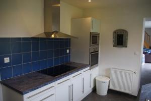 una cocina con armarios blancos y azulejos azules en la pared en Villa Audresselles, en Ambleteuse
