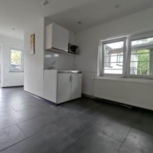 an empty kitchen with white walls and windows at Modernes einzimmer Apartment in Hügelsheim +25 photos