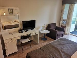 Una habitación con un escritorio con televisión y una cama. en Huoneisto 452 Span viereisessä talossa 4krs, en Kilvakkala