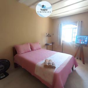a bedroom with a pink bed with two sandals on it at LAGOA I - Saquarema RJ in Saquarema