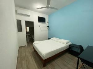 une chambre avec un lit blanc et un ventilateur de plafond dans l'établissement Posada Coral, à Santa Cruz Huatulco