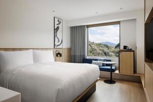 垂水市にあるFairfield by Marriott Kagoshima Sakurajimaのベッドと大きな窓があるホテルの部屋