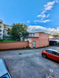 a red car parked in a parking lot next to a building at Studio - Hyper Centre avec Parking & Wifi Gratuit in Grenoble