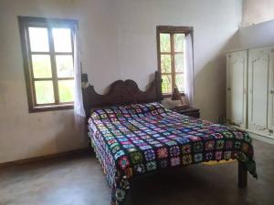 a bedroom with a bed with a quilt and two windows at Vila do Salitre - Casa a 5 min de lagos e cachoeiras in Extração +13 photos