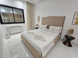 a white bedroom with a large bed and a window at Secret Place in Hammam Sousse
