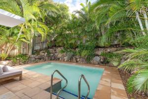 a swimming pool in a yard with palm trees at 4-18 Peregian Esplanade, Peregian Beach QLD 4573 in Peregian Beach