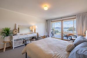 a bedroom with a bed and a desk with a mirror at Wanda Up, 80 Randall Dr - spectacular views, aircon and Wi-Fi in Salamander Bay