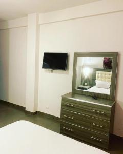 ein Schlafzimmer mit einer Kommode mit einem Spiegel und einem TV in der Unterkunft CosyServives in Grand Médina