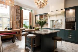 a kitchen with green cabinets and a counter with stools at The Balcony Luxury Apartment in Berwick-Upon-Tweed