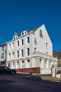 a white building with a car parked in front of it at The Balcony Luxury Apartment in Berwick-Upon-Tweed