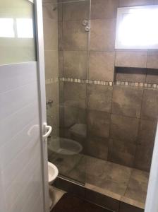 Un baño con ducha, inodoro y lavabo. en Cuatro Elementos Housing, en Villa Santa Cruz del Lago