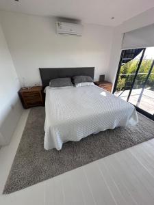 a bedroom with a white bed and a large window at Enigma in José Ignacio +38 photos