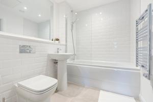 a white bathroom with a toilet and a tub and a sink at City Centre Birmingham 1-Bed with WiFi and Parking in Birmingham