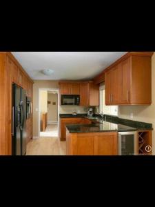 a kitchen with wooden cabinets and a black refrigerator at Spacious West Kelowna Home that is great for family, friends, or business trip! in West Kelowna