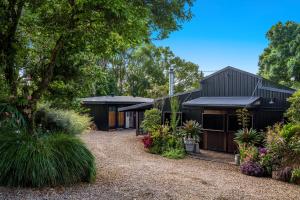 a black house with plants in front of it at The Bangalow Barn in Bangalow