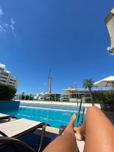 a person laying on a chair next to a swimming pool at o MELHOR DA PRAIA BRAVA !!! in Itajaí