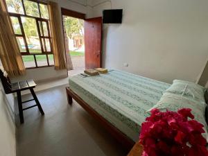 a bedroom with a bed with flowers and a window at Stone House Mancora in Máncora