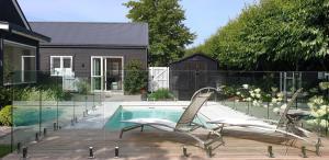 a swimming pool with two chairs next to a house at Westwood Country House, Studio Apartment, Greytown in Greytown