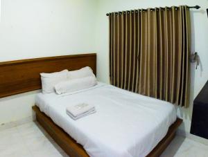 a bedroom with a bed with white sheets and a window at Balmoral House Ambarukmo in Yogyakarta