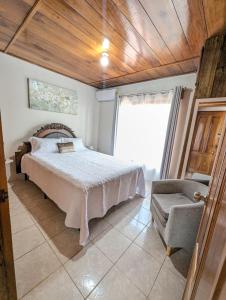 a bedroom with a bed and a chair at Departamento Ángeles del Arenal #2 in Fortuna