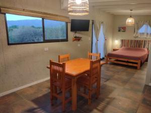 Un comedor con una mesa y sillas y una cama. en El Colibrí de los Molles, en Los Molles