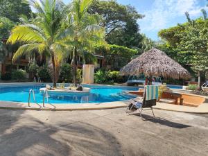 a swimming pool with a chair and a umbrella at Condominio Coco Marindo #34 in Coco