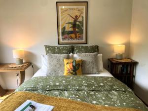 a bedroom with a bed with a green comforter and two lamps at Gully hideaway apartment in Hamilton