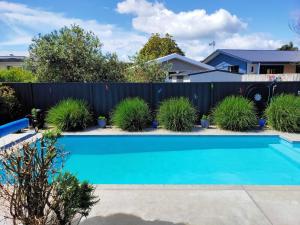 a blue swimming pool in front of a fence at Lakaz Beach house in Omokoroa
