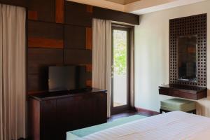 a bedroom with a bed and a tv and a window at Bali Ula Villa in Nusa Dua