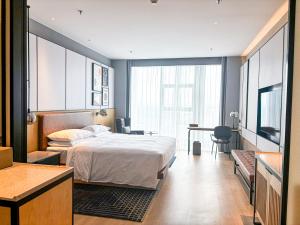 a bedroom with a bed and a desk and a table at Four Points by Sheraton Datong Pingcheng in Datong