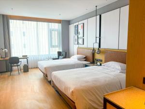 a hotel room with two beds and a desk at Four Points by Sheraton Datong Pingcheng in Datong
