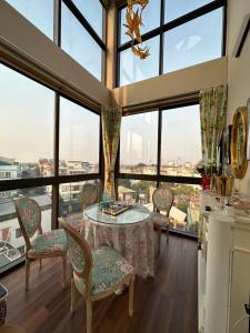 a room with a table and chairs and large windows at The Hota House in Hanoi
