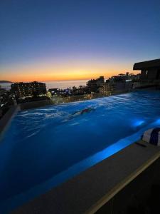 a large blue swimming pool with a view of the city at Céntrico Estudio Con Roof Top Zona Romántica 502 in Puerto Vallarta