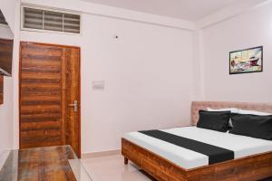 a bedroom with a bed and a wooden door at Super Hotel O Neelbad Guest House in Bhopal