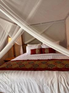 a bed with a white canopy and red pillows at Melati bali villa in Canggu